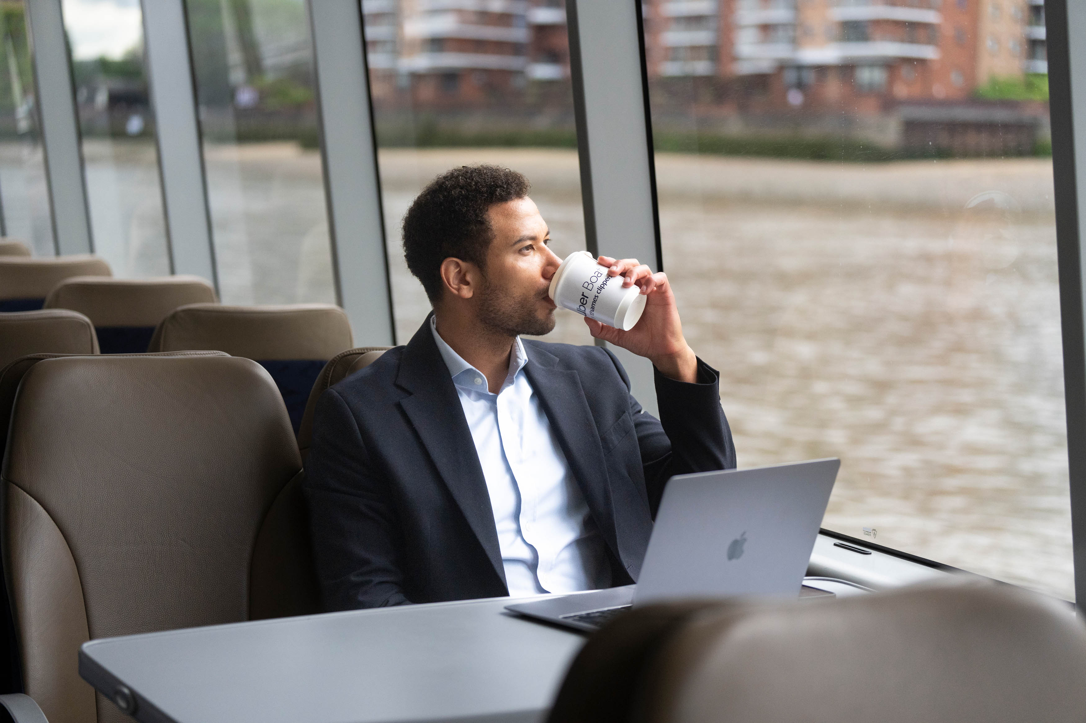 Commuter with laptop by the window drinking coffee